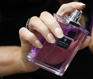 A woman sprays perfume from a bottle of Victoria Beckham's 'Signature' fragrance at Harvey Nichols in Manchester